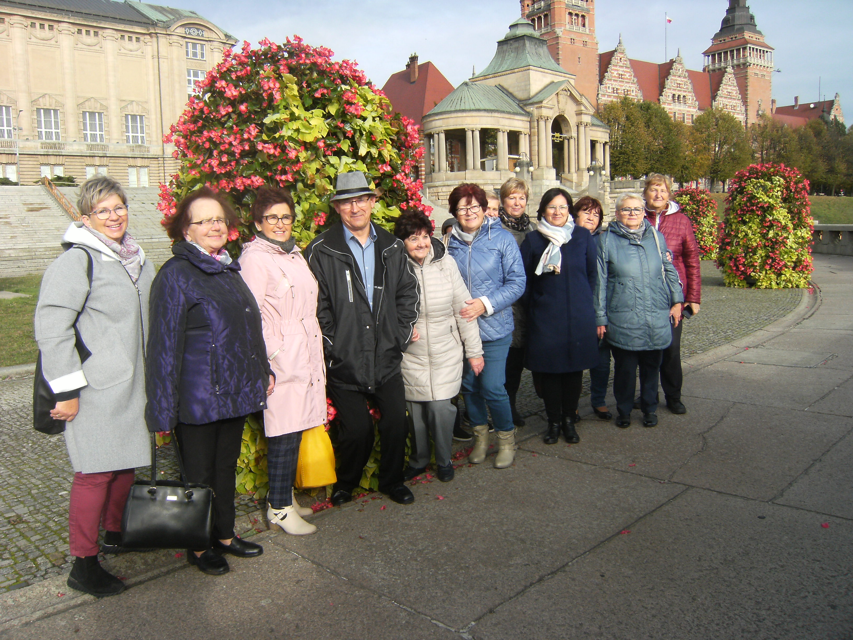 Grupa seniorów ubrana w lokalne stroje ustawiona do zdjęcia grupowego. W środku dwie kobiety ubrane na czarno. 